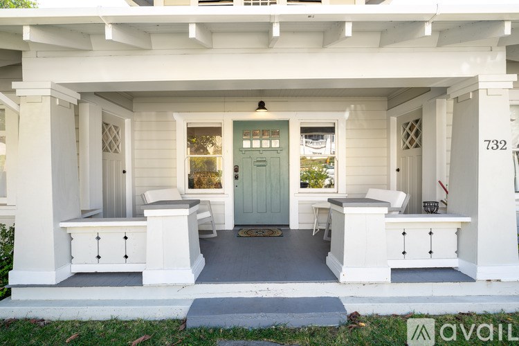 A white porch with a blue door and a sign that says 732.