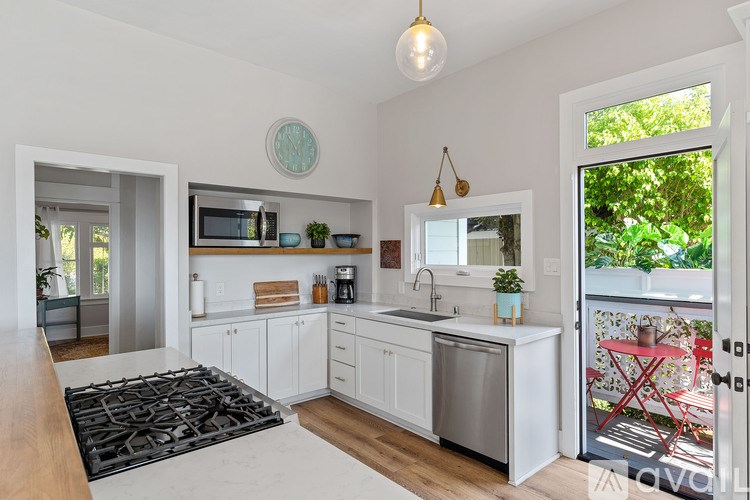 A modern kitchen with white cabinets and a black stove top.