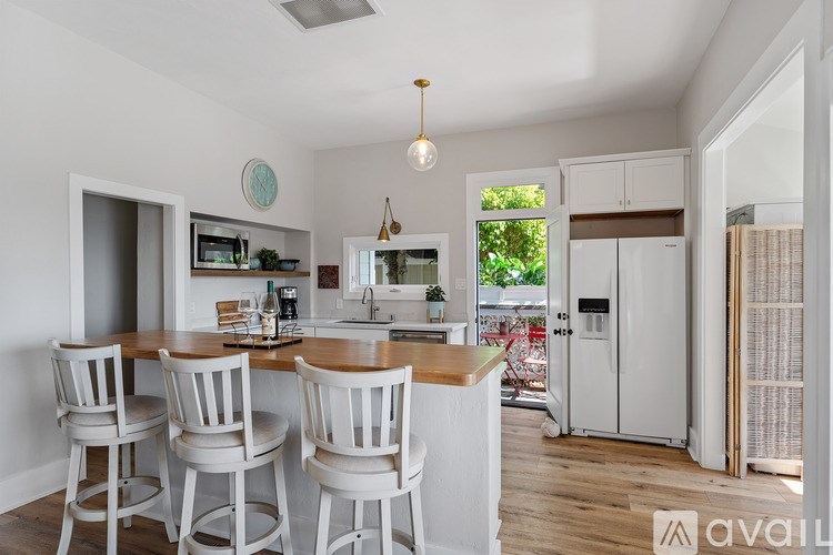 A kitchen with white chairs and a wooden table.