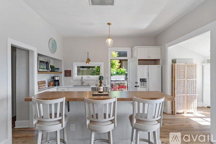 A kitchen with a table and chairs in the foreground and a window in the background.