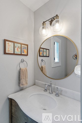 A bathroom with a round mirror and a white sink.