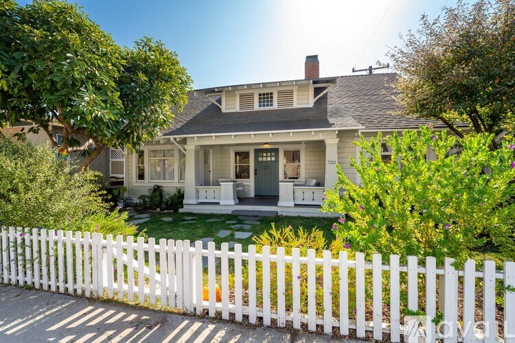 A white picket fence surrounds a charming two-story house.
