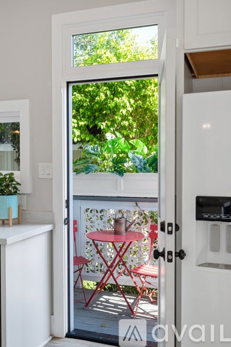 A white door with a glass window leading to a red table and chairs outside.