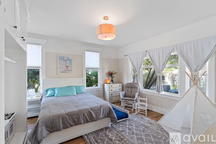 A bedroom with a bed, chair, and a teepee tent.