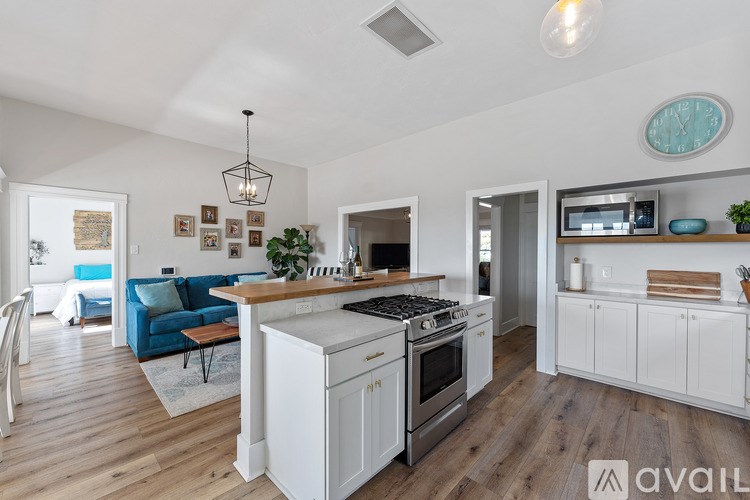 A kitchen with a white stove top oven and white cabinets.