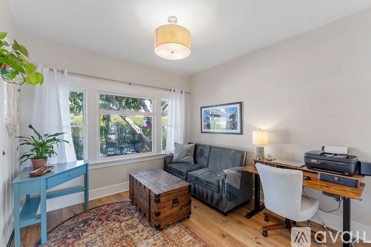 A living room with a grey couch, a blue desk, and a wooden coffee table.