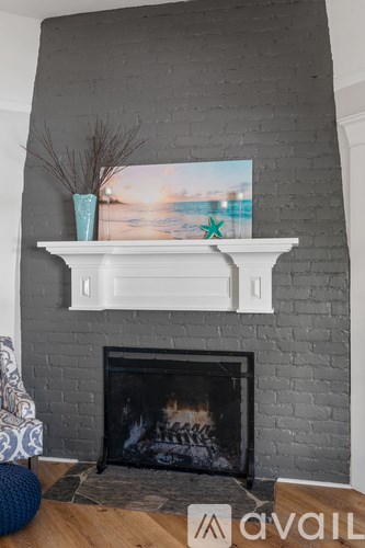 A fireplace with a painting above it and a vase on the mantle.