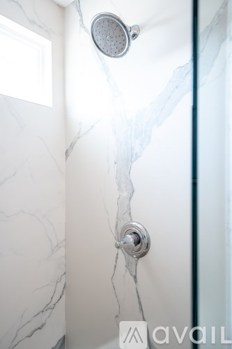 A shower head with a cracked wall behind it.