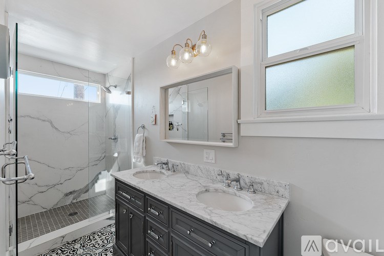 A bathroom with a marble countertop and a large mirror above the sink.