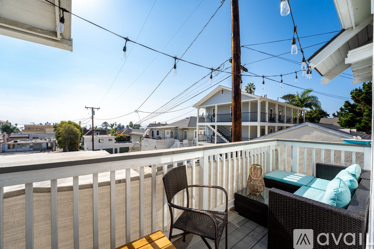 A balcony with a chair and a couch with a view of houses and trees.