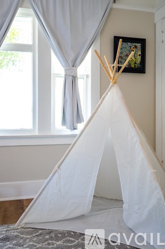 A white teepee in a room with a window and a picture on the wall.