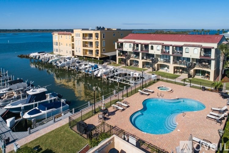 A marina with boats docked in front of a building with a pool.