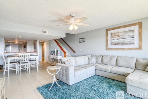 A living room with a white couch and a dining table.