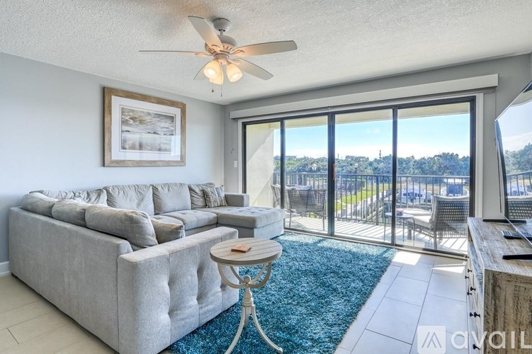 A living room with a grey couch and a ceiling fan.