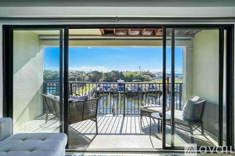 A balcony with a table and chairs overlooking a pool and a view of the ocean.