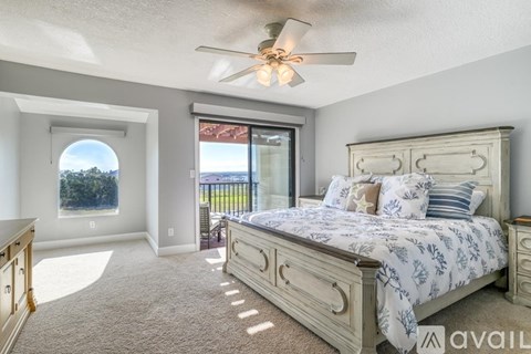A bedroom with a large bed and a ceiling fan.