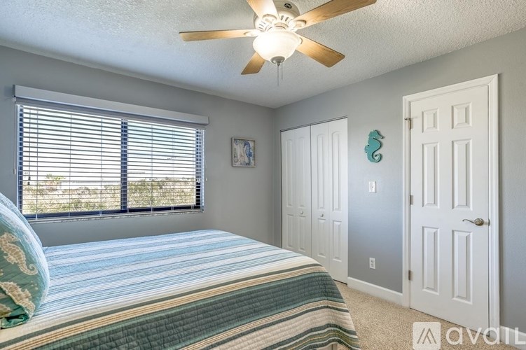 A bedroom with a bed, a ceiling fan, and a window with blinds.