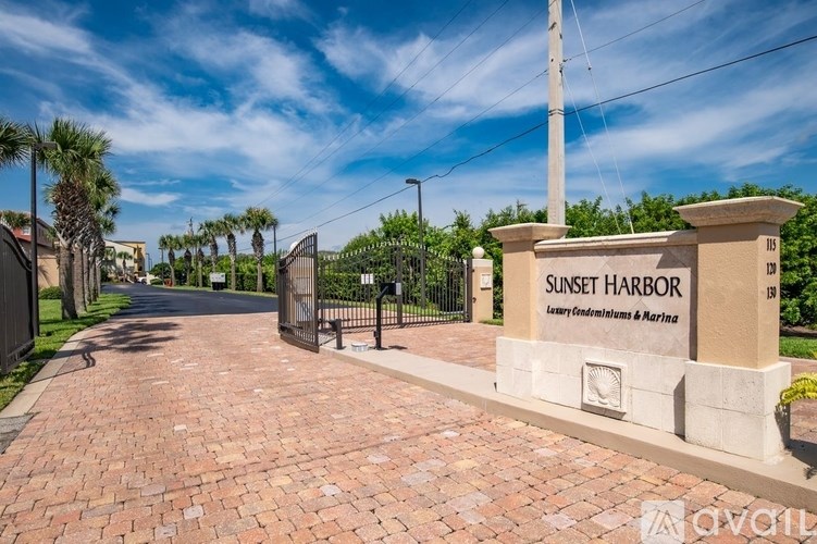 The image shows a gated entrance to Sunset Harbor with a sign that reads "Luxury Estates & Marina."
