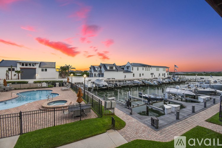 A marina with boats docked and a pool area with a sun lounger.