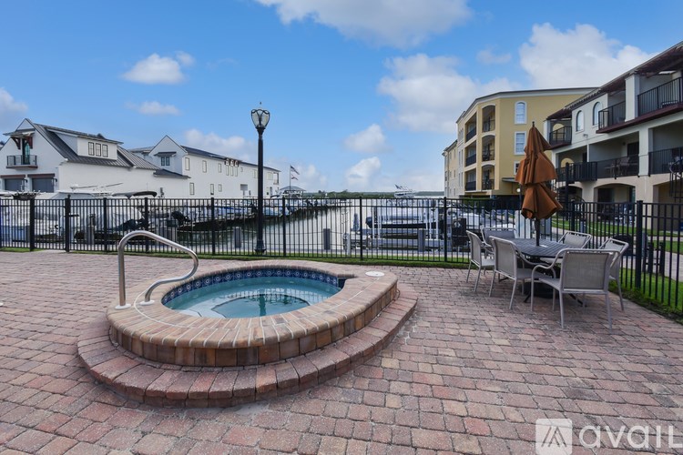 A patio with a hot tub and chairs is surrounded by a black fence.