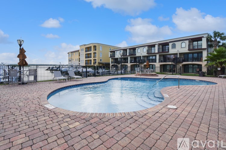 A pool surrounded by a brick patio in front of a building.