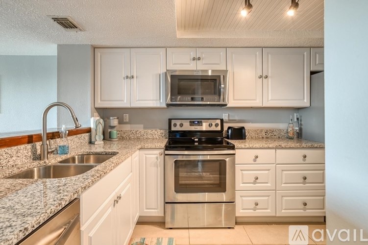 A kitchen with white cabinets and granite countertops.
