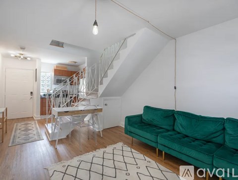 A living room with a green couch and a white staircase.