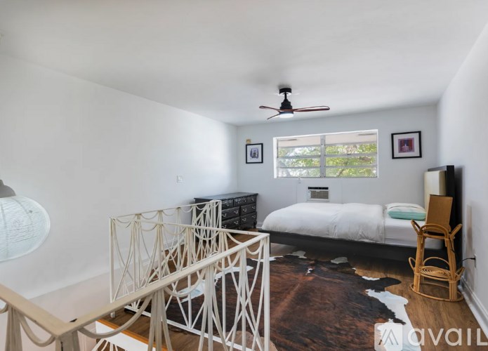 A bedroom with a bed, chair, and a fan.