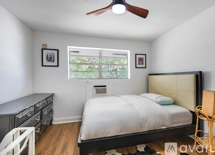 A bedroom with a bed, dresser, and window.