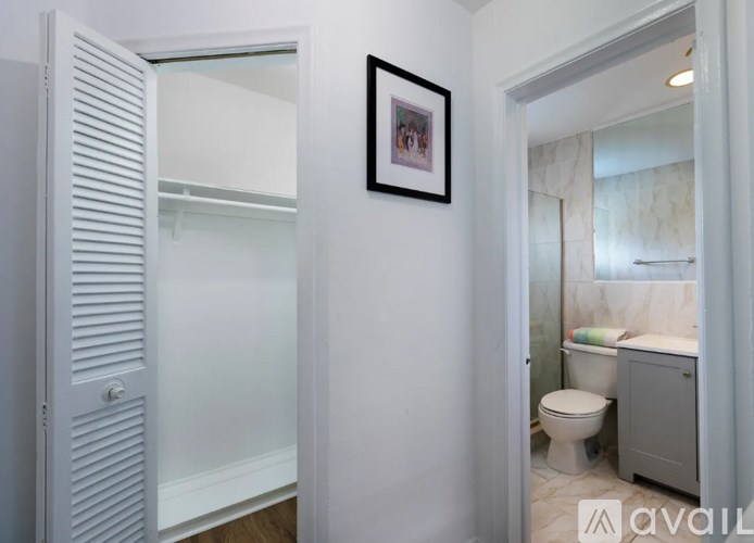 A bathroom with a toilet, sink, and a picture on the wall.