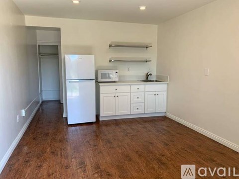 A kitchen with white appliances and cabinets in a room with wood flooring.