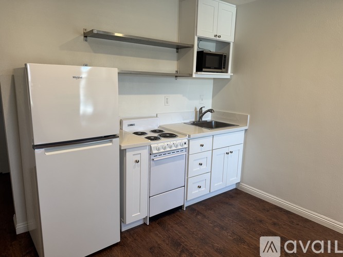 A white fridge and microwave in a kitchen with white cabinets.