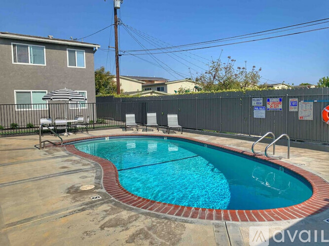 A black fence surrounds a small pool in a backyard.