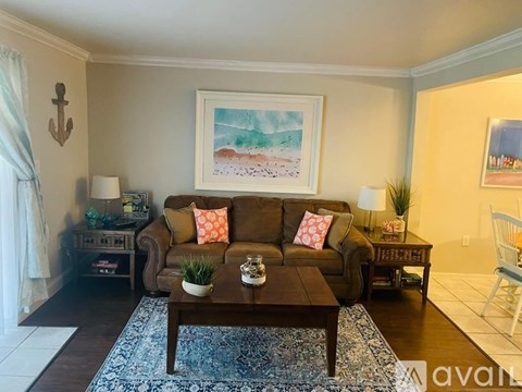 A living room with a brown couch, a coffee table, and a painting on the wall.