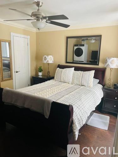 A bedroom with a bed, two lamps, and a mirror.