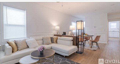 A living room with a white sofa, a round table, and a dining table with chairs.