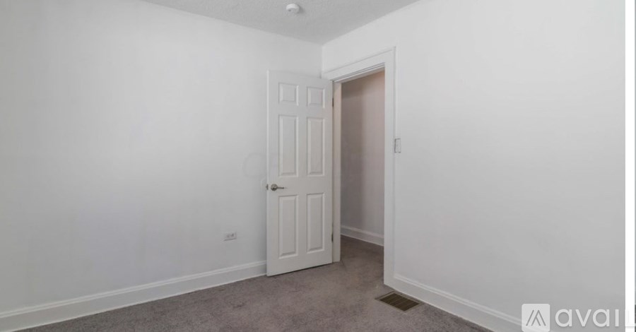 A room with a white door and carpeted floor.