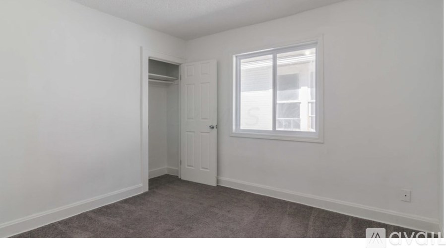 A room with a carpeted floor, a door, and a window.