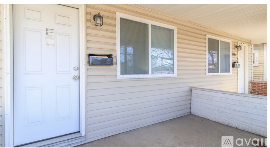 A white door is on the left of a house with a window and a small porch.