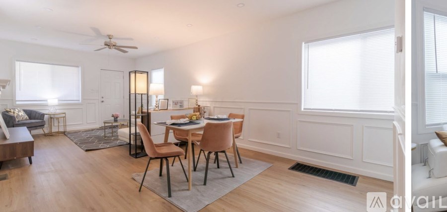 A dining room with a table set for two and a couch.