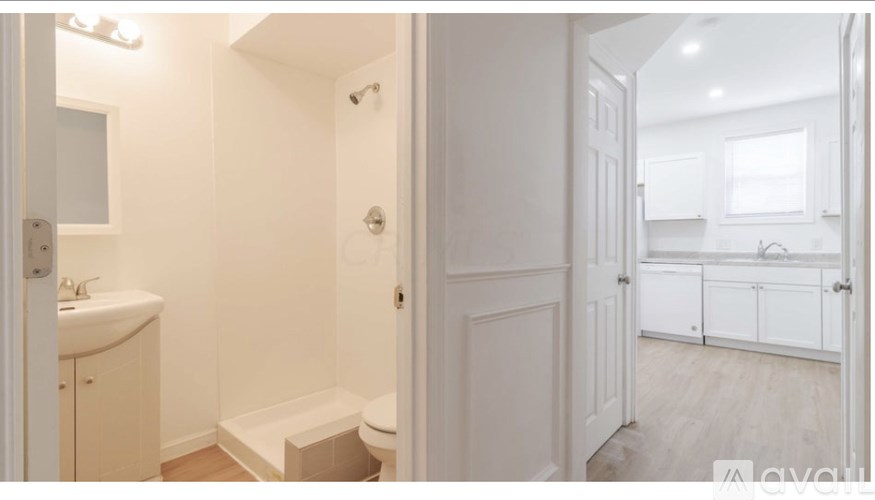 A white bathroom with a toilet, sink, and shower.