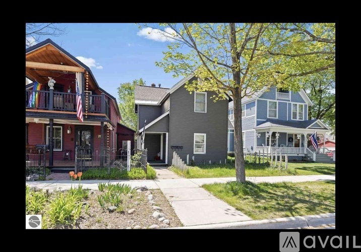 A row of houses with a tree in front of the grey house.