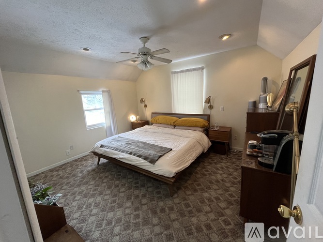 A bedroom with a bed, dresser, and ceiling fan.