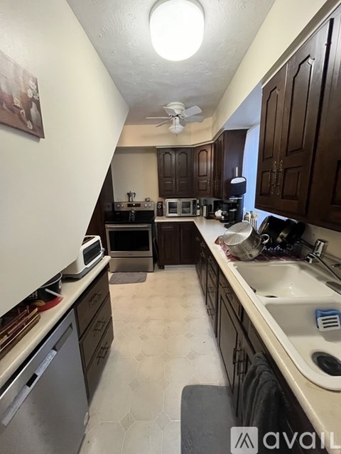 A kitchen with brown cabinets and a white dishwasher.