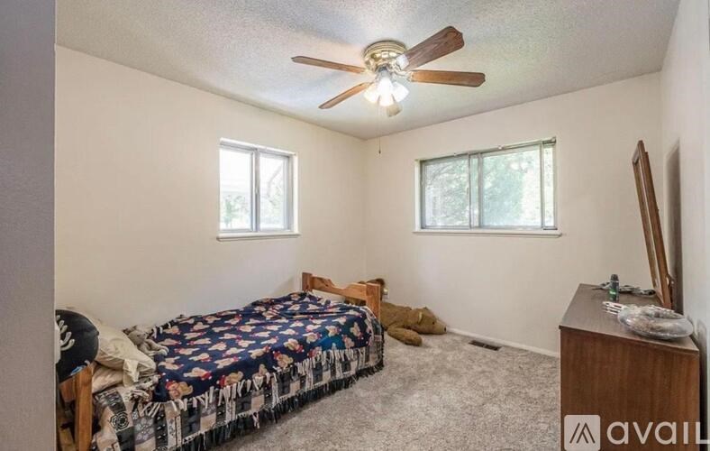 A bedroom with a bed, dresser, and ceiling fan.