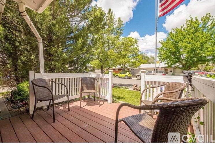 A wooden deck with two chairs and a flag on a pole.