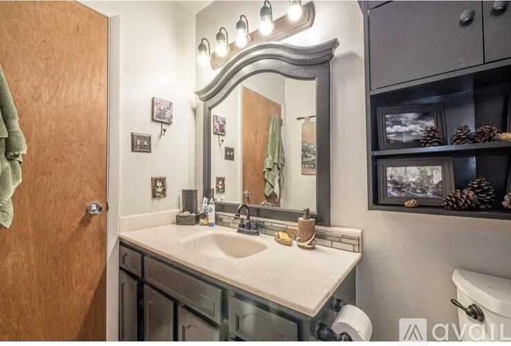 A bathroom with a sink, mirror, and a towel hanging on the door.