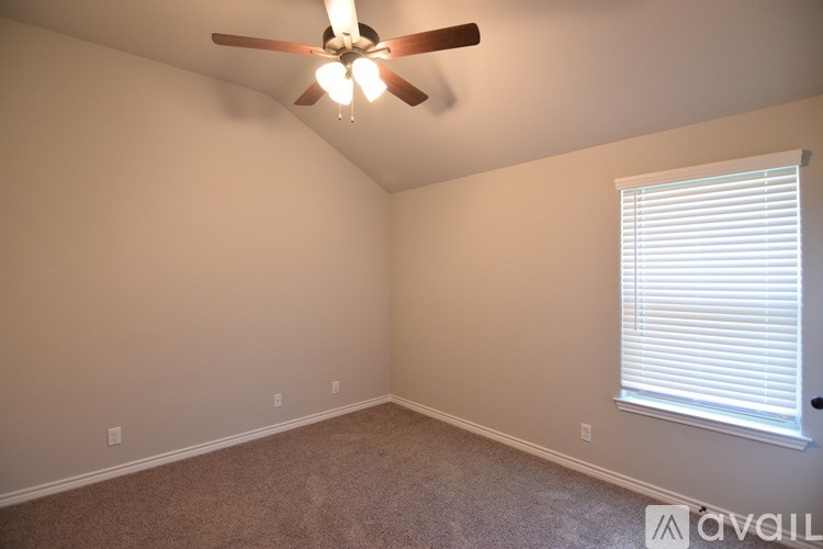 A room with a ceiling fan and a window with blinds.