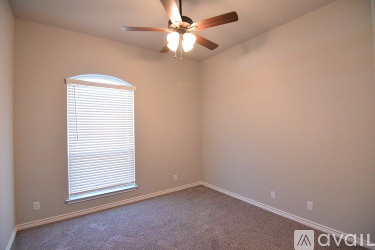 A room with a ceiling fan and a window with blinds.