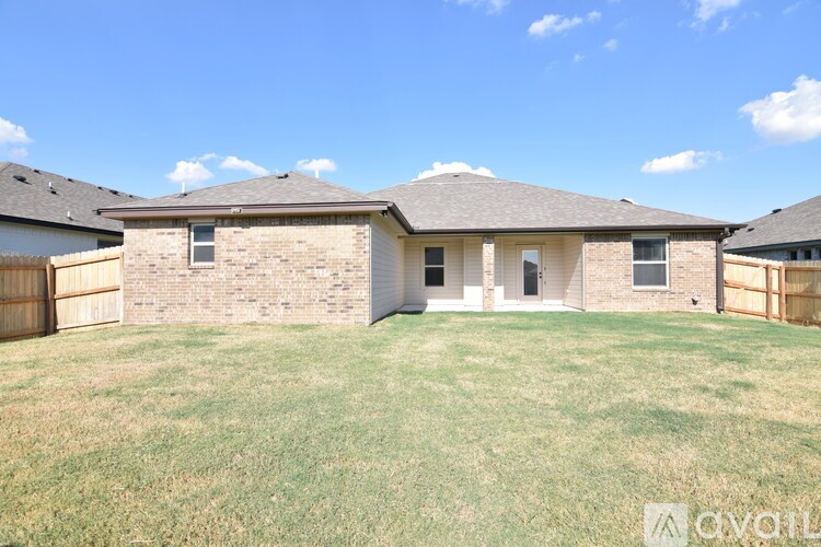 A house with a brown roof and a white fence is for sale.